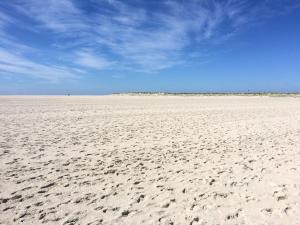 an empty beach with footprints in the sand at Ferienwohnung *Meeresleuchten* in Wittdün +9 photos