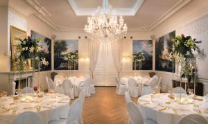 ライデンにあるBoutique Hotel Huys van Leydenの白いテーブルと椅子、シャンデリアのある宴会場