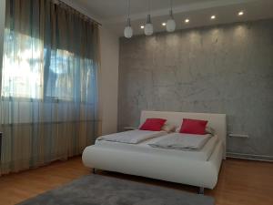 1 dormitorio con 1 cama blanca y 2 almohadas rojas en Ars Duo en Novi Sad