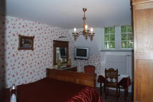 una camera con letto, scrivania e TV di B&B Les Genêts a Hatrival