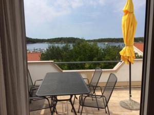 een balkon met een tafel en stoelen en een parasol bij APARTMAN I SOBE MARIJANA in Rab