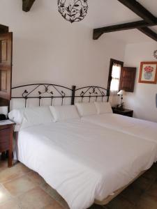 
a large white bed sitting in a bedroom next to a wall at Hotel Rural Xerete in Navaconcejo
