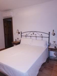 
a white bed sitting in a bedroom next to a wall at Hotel Rural Xerete in Navaconcejo
