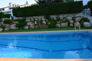 einem blauen Pool vor einer Steinmauer in der Unterkunft Casas Blanca 19 piscina barbacoa wifi in Tossa de Mar