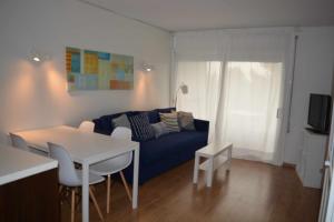 a living room with a blue couch and a table at Cala LLevado Tossa de M. A/C Parking Piscina in Tossa de Mar