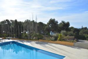 a swimming pool with blue water and trees in the background at Cala LLevado Tossa de M. A/C Parking Piscina in Tossa de Mar
