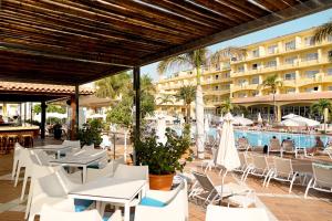 um pátio no resort com mesas e cadeiras e uma piscina em R2 Buganvilla Hotel & Spa em Morro del Jable