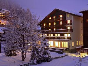 a building with a tree in the snow at Hotel Alphubel in Zermatt