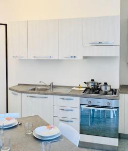 uma cozinha com armários brancos e uma mesa com pratos em Margherita 8 Apartments em Rimini