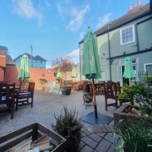 eine Terrasse mit Stühlen, einem grünen Sonnenschirm und Tischen in der Unterkunft The Quay in Faversham