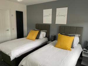 two beds with yellow pillows in a room at The apartment at Glendaruel in Portree