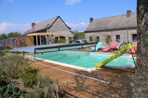 a swimming pool with a slide in front of a house at le clos du fourmanoir in Avesnelles