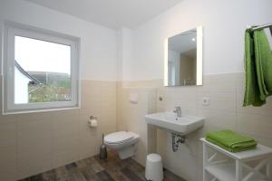 a white bathroom with a toilet and a sink at F-1037 Ferienhaus Neuendorf Haus Terrasse, Gartennutzung, Meerblick in Lauterbach +10 photos