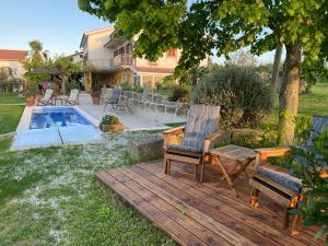 een houten terras met 2 stoelen en een zwembad bij Med oljkami Apartment in Koper