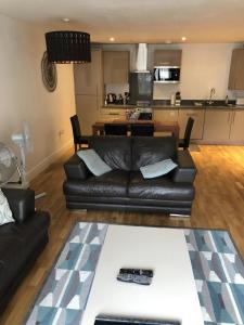 a living room with a black leather couch and a kitchen at Stockley Near Heathrow in Yiewsley