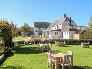 a garden with tables and chairs in front of a building at Lower Farm Cottage in Weymouth