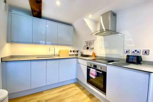 a kitchen with white cabinets and a stove top oven at Tilly's a perfect apartment in the Market Town of Ledbury in Ledbury