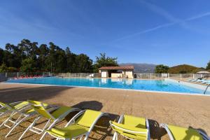 a group of lawn chairs sitting next to a swimming pool at Résidence U Nebbiu in Olmeta-di-Tuda