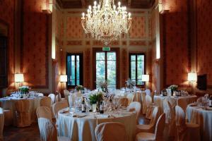 una stanza piena di tavoli e sedie con un lampadario a braccio di Villa Pitiana a Donnini
