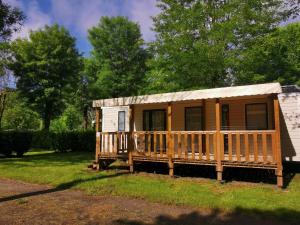 a wooden cabin with a porch in the grass at Camping Paradis le Rocher de la Granelle in Le Bugue