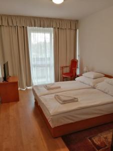 sypialnia z dużym łóżkiem i dużym oknem w obiekcie PSZ Hotel Beach Földvár w Balatonföldvárze