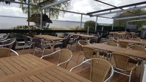 a patio with wooden tables and chairs and the water at Paolos Seehotel Mardorf in Mardorf