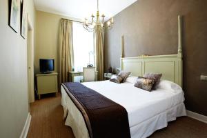 a bedroom with a large white bed and a chandelier at KAIAN MAITEA in Plentzia