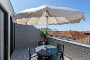 a patio table with an umbrella on a balcony at Nell&And&Jess in Espinho