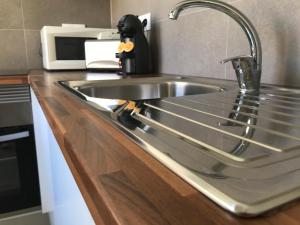 a stainless steel sink in a kitchen with a microwave at Casas da Praia in Manta Rota +42 photos
