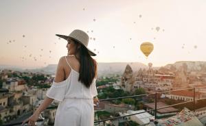 a woman in a hat looking at hot air balloons at Henna Hotel-Adults Only in Goreme