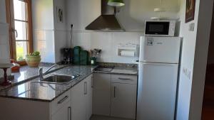 uma cozinha com um frigorífico branco e um lavatório em Albergue El Pino em Cóbreces