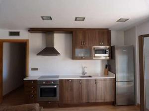 cocina con armarios de madera y nevera de acero inoxidable en Apartamentos Puerta de Ordesa, en Laspuña