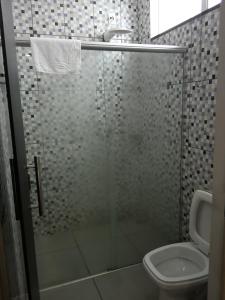 uma casa de banho com uma cabina de duche em vidro e um WC. em POUSADA FAROL DE ALEXANDRIA LTD - ME em Cândido Mota