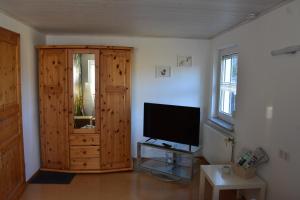 a living room with a television and a wooden cabinet at Zimmer Bärbel in Förbau