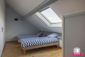 two beds in a attic room with a window at Le Duplex Ensoleillé du Parc * Parking * Balcon * in Orléans