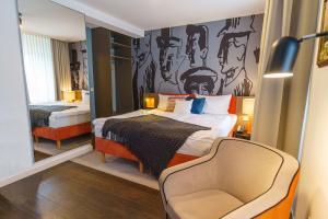 a bedroom with a bed and a chair in it at Tante ALMA's Bonner Hotel in Bonn