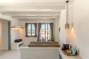 een witte kamer met een bed en een raam bij Paros Cape Suites in Naousa
