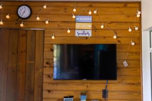 a flat screen tv hanging from a wall with a clock at Casa Container - Pousada Container da Montanha AZUL in Rio Fortuna