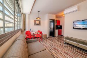 een woonkamer met een bank en een tafel met rode stoelen bij Ben Yehuda Apartments in Tel Aviv