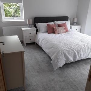 a bedroom with a white bed with pink pillows at Loch Ness House Blairbeg in Drumnadrochit