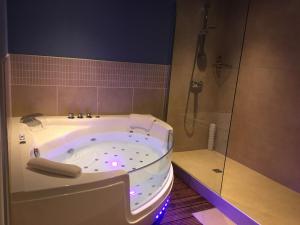 een badkamer met een groot bad en een douche bij Hôtel Des Argousiers in Ambleteuse