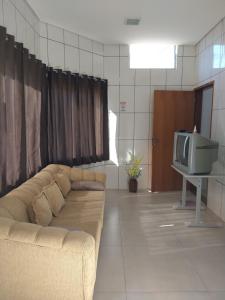 uma sala de estar com um sofá e uma televisão em Espaço coração de mãe em Pirapozinho