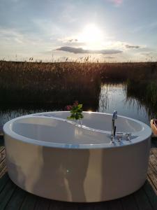 une baignoire assise sur un quai à côté d'une masse d'eau dans l'établissement Pfahlbau Rust/Neusiedlersee Sunset II, à Rust