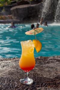 a drink in a glass next to a swimming pool at Chalé Praia de Minas in São Lourenço