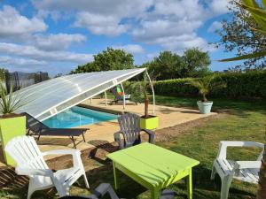 eine Terrasse mit einem Tisch, Stühlen und einem Pool in der Unterkunft Gite de kernaet avec piscine in Plougonvelin