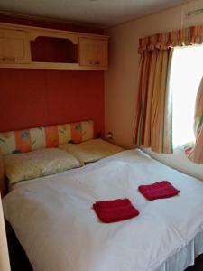 a bedroom with a white bed with two red towels on it at Rybník Dalibor I in Vlcice
