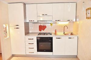 a kitchen with white cabinets and a stove and a sink at Olimpia House - Central Station in Bari