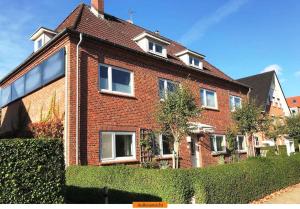 ein rotes Backsteinhaus mit Fenstern und einer Hecke in der Unterkunft Austernfischer in Wyk auf Föhr