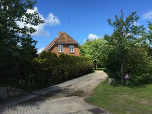 a brick house with a tree in front of a driveway at Ferienhaus Ellen, OG Whg in Utersum