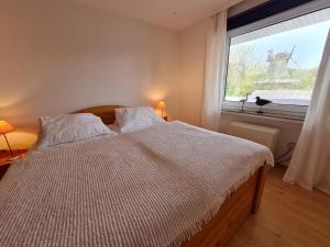 Schlafzimmer mit einem Bett und einem großen Fenster in der Unterkunft Wattwurm in Wyk auf Föhr